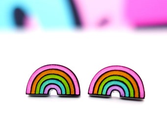 Op de afbeelding: Een paar regenboogkleurige oorbel studs. De oorbellen zijn gevormd als regenbogen met roze, oranje, gele, groene, blauwe en paarse strepen.