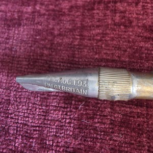 K&ouml;nnte beinhalten: Ein metallisches Werkzeug mit einem spitz zulaufenden Ende und einem gerippten zylindrischen Abschnitt. Die Metalloberfl&auml;che weist eine Pr&auml;gung mit dem Text PAT. AUG. 1. 93. und PAL. GT. BRITAIN auf, was auf ein Patent vom 1. August 1893 hinweist.