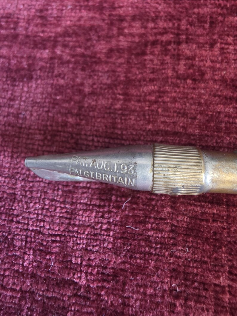 K&ouml;nnte beinhalten: Ein metallisches Werkzeug mit einem spitz zulaufenden Ende und einem gerippten zylindrischen Abschnitt. Die Metalloberfl&auml;che weist eine Pr&auml;gung mit dem Text PAT. AUG. 1. 93. und PAL. GT. BRITAIN auf, was auf ein Patent vom 1. August 1893 hinweist.