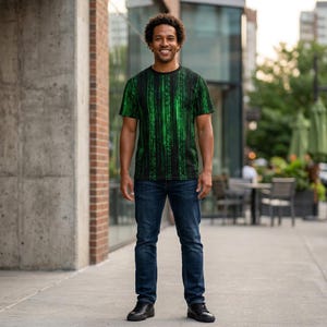 May include: A black t-shirt with a green digital rain pattern. The short-sleeved shirt is worn with blue jeans and black shoes. The person is standing on a sidewalk in front of a building.