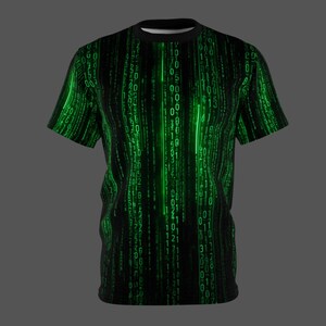 May include: Black t-shirt with a green binary code design. The graphic features vertical lines of green numbers and symbols, creating a digital rain effect. The shirt has a black collar and short sleeves, perfect for a tech or sci-fi enthusiast.