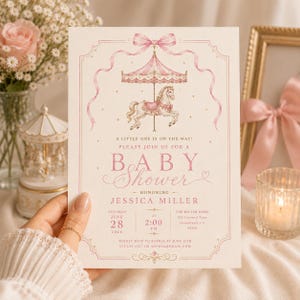 Può includere: Invito per baby shower rosa chiaro con un design a giostra. L'invito include un cavallo della giostra, un baldacchino rosa e le parole "Baby Shower". Sono inclusi anche data, ora e luogo.