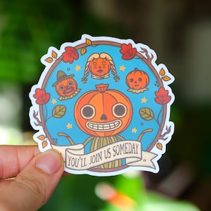 May include: A circular sticker featuring a smiling orange pumpkin-headed character with a wide grin, surrounded by other pumpkin-like figures and autumn leaves. The sticker has the text "YOU'LL JOIN US SOMEDAY" on a banner.