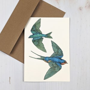 May include: A greeting card featuring a pair of blue and green swallows in flight against a white background.