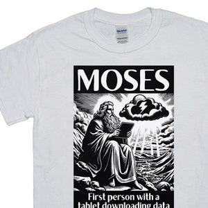 May include: White t-shirt with a black and white graphic of Moses holding a tablet, with the text "MOSES" above and "First person with a tablet downloading data from the cloud." below. The graphic depicts Moses seated on a rocky landscape.
