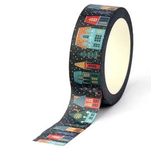 May include: A roll of black washi tape featuring a repeating pattern of colorful houses and evergreen trees against a dark background with white dots representing falling snow. The tape has a smooth texture and a central white cardboard core.
