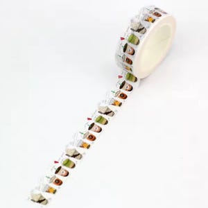 May include: A roll of decorative washi tape with a repeating pattern of illustrated bubble tea drinks in various colours. The tape is white with a light beige core and is unrolled to show the pattern.