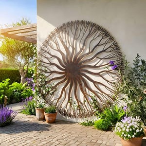 Op de afbeelding: Een groot, cirkelvormig metalen wandkunstwerk dat lijkt op een boomwortelsysteem. Het kunstwerk heeft een roestbruine kleur en is op een witte muur gemonteerd. De scène is buiten, met potplanten en een tuin zichtbaar.