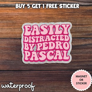 Könnte beinhalten: Ein rosa Aufkleber mit dem Text "EASILY DISTRACTED BY PEDRO PASCAL" in einer Retro-Schriftart. Der Aufkleber hat einen glitzernden Rand und das Wort "waterproof" steht unten. Ein kleiner rosa Kreis zeigt an, dass es sich um einen Magneten oder Aufkleber handelt.