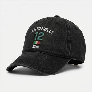 May include: Black baseball cap with the name "Antonelli" embroidered in white, the number "12" in green, and a small Italian flag. The word "Kimi" is embroidered below the flag. The cap has a curved brim.