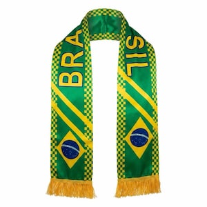 Può includere: Una sciarpa in raso verde con un bordo a scacchi gialli e frange gialle alle estremità. La sciarpa mostra la scritta BRAZIL in grassetto giallo e include una forma a rombo gialla contenente un cerchio blu con stelle bianche.