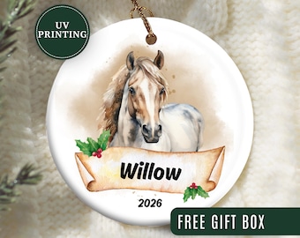 May include: A round, white ceramic ornament featuring a watercolor painting of a horse's head. The horse has a tan and white coat with a flowing mane. The name "Willow" is written on a banner, with the year "2026" below. The ornament has a gold string for hanging.