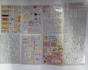 Peut inclure: Plusieurs feuilles d'autocollants avec divers motifs mignons. Les autocollants présentent des animaux de dessins animés, des aliments comme des sushis et des éléments décoratifs. Les feuilles ont une finition scintillante et irisée, avec des couleurs pastel.