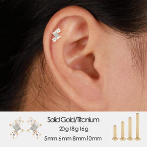 Pode incluir: Uma orelha com um brinco de ouro e diamantes. O brinco apresenta um design de cluster com diamantes de corte retangular e redondo. A imagem inclui o texto: "Solid Gold/Titanium 20g 18g 16g 5mm 6mm 8mm 10mm."
