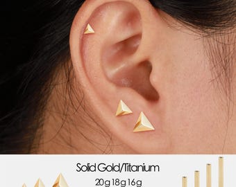 May include: Gold triangle stud earrings in various sizes are displayed on an ear. The text reads "Solid Gold/Titanium" and lists sizes 20g 18g 16g and 5mm 6mm 8mm 10mm. Additional gold posts are shown.