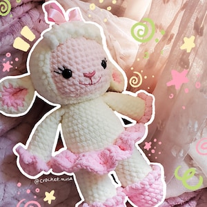 May include: A handmade crochet lamb doll in white and pink. The lamb has a pink face, ears, and feet, with a white body and a pink tutu. The doll has a pink bow on its head and the text "@crochet.musa" is visible.