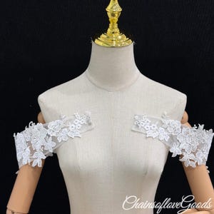 May include: White lace off-the-shoulder sleeves with floral detailing. The sleeves are displayed on a mannequin, showcasing the delicate design and texture. The text "ChainsofloveGoods" is visible at the bottom.