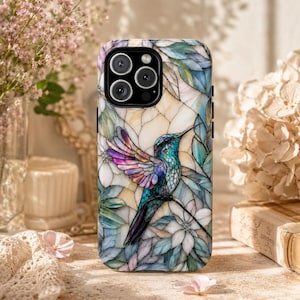 May include: A smartphone case featuring a stained glass style design of a hummingbird with iridescent purple and teal wings perched among white flowers and green leaves. The artwork covers the entire back of the case, including the camera cutout.