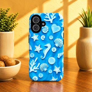 May include: A blue phone case featuring a sea-themed design. The case has a pattern of white seashells, starfish, seahorses, and bubbles. The case is designed to fit a smartphone and has cutouts for the camera and buttons.