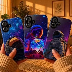 May include: Three phone cases with space-themed designs. One case features a galaxy and astronaut helmet, another shows an astronaut holding a glowing Earth, and the third depicts an astronaut in a spacesuit against a purple nebula.