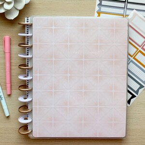 May include: A planner with a pink geometric cover, gold-colored disc binding, and a set of colorful planner stickers. Two pens, one pink and one white, are also visible. The white pen has the text "Light up my Life".