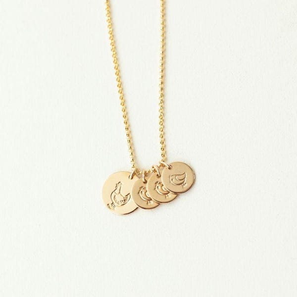 May include: A gold-colored necklace featuring a delicate chain and four circular pendants. Each pendant is engraved with a different bird design. The necklace is displayed against a plain white background, highlighting the jewelry's details.