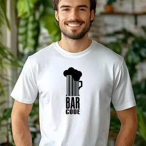 May include: White t-shirt with a black graphic of a beer mug formed by a barcode, topped with a black foam design. The text "BAR CODE" is printed below the mug in a bold, sans-serif font. The shirt is worn by a person.