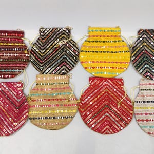 Può includere: Otto sacchetti rotondi con coulisse in vari colori, tra cui rosso, giallo e nero. Ogni sacchetto è adornato con paillettes e perline in una varietà di motivi, con una chiusura a coulisse color oro. I sacchetti sono probabilmente usati per piccoli oggetti o regali.