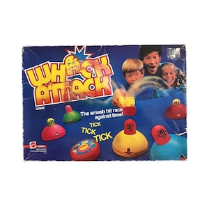 May include: A vintage "Whack Attack" board game box with a blue background. The game features colorful plastic figures and the text "Whack Attack" in yellow and red. The box also shows a family playing the game.