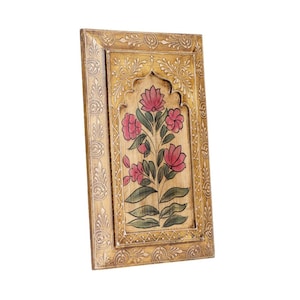 May include: Wooden wall art with a floral design. The artwork displays pink flowers and green leaves on a light brown backdrop. The frame is a light gold colour with detailed carvings.