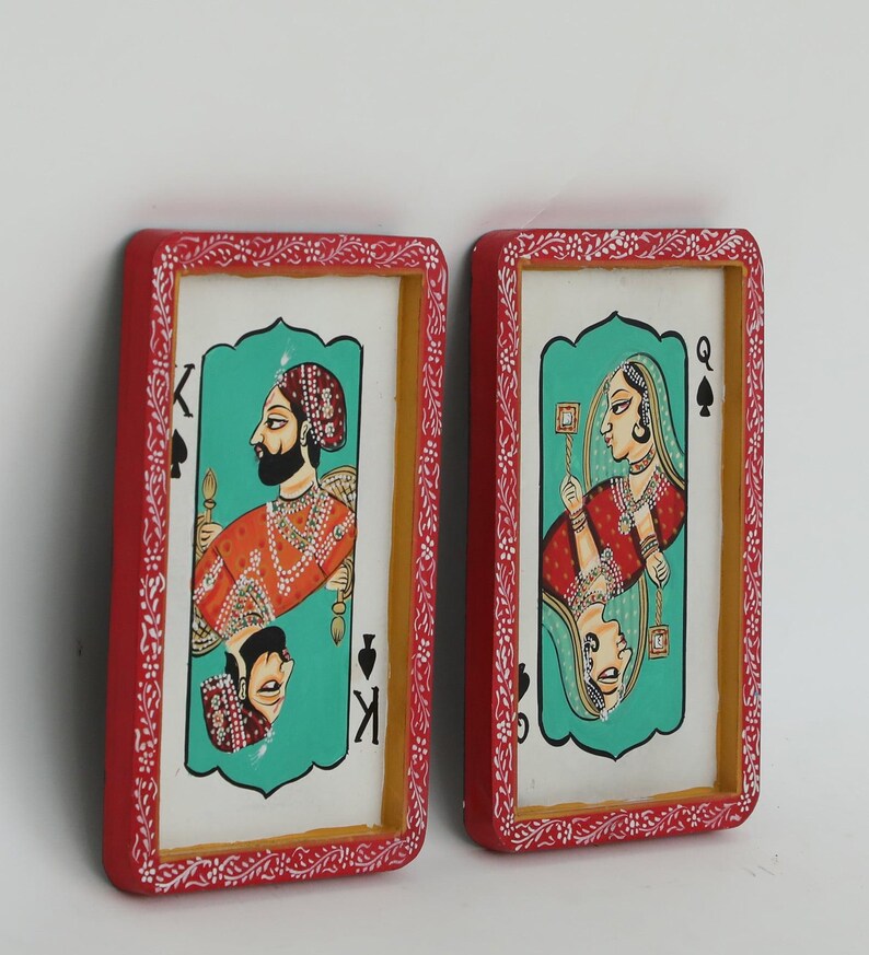 K&ouml;nnte beinhalten: Zwei gerahmte Spielkarten-Kunstwerke. Eines zeigt einen K&ouml;nig in Orange und Gold, das andere eine K&ouml;nigin in Rot und Gold. Beide haben einen t&uuml;rkisfarbenen Hintergrund und sind rot mit wei&szlig;en floralen Akzenten gerahmt.