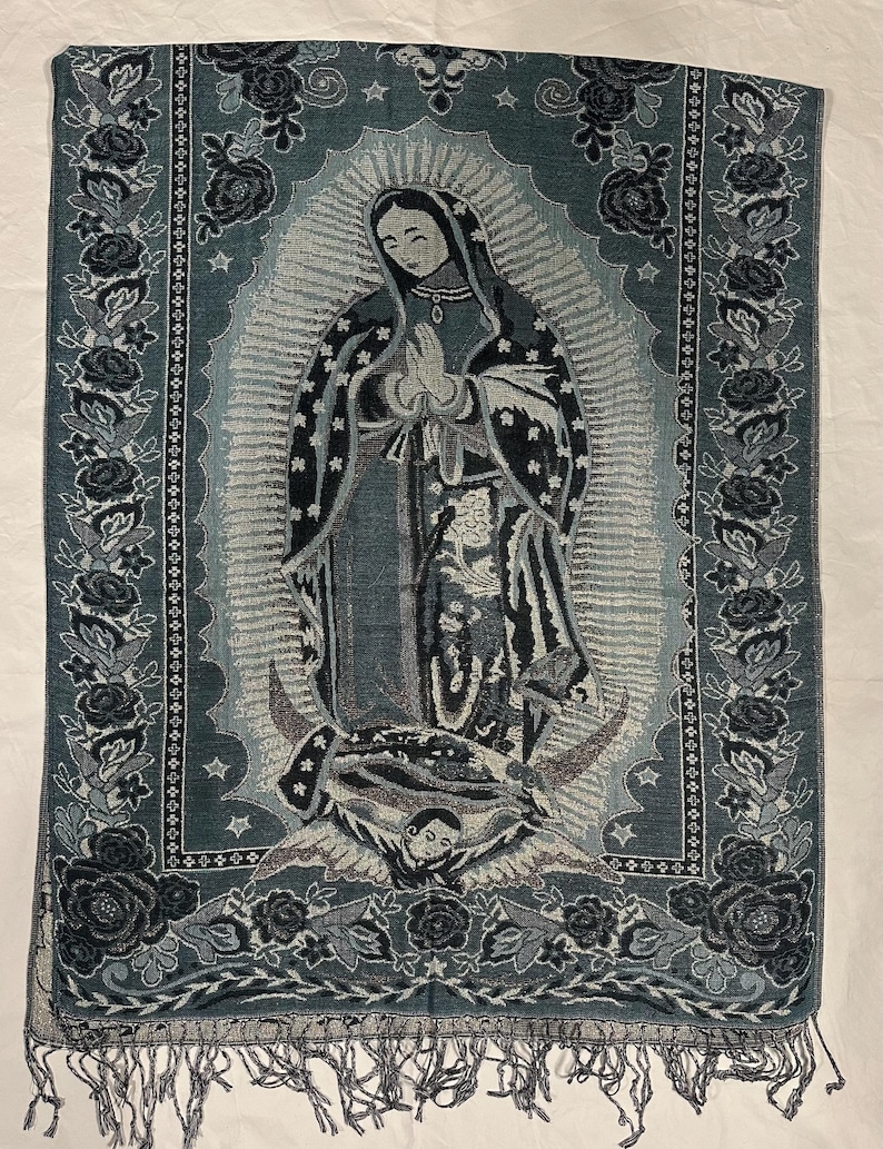 May include: A teal and grey tapestry depicting the Virgin Mary with a halo and clasped hands. The tapestry has a floral border and fringe at the bottom. The image is centered on a white background.