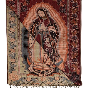 May include: A tapestry featuring an image of the Virgin Mary with a halo, hands clasped in prayer. The tapestry has a burgundy background with floral and star patterns, and a fringe at the bottom. The image is framed by a floral border.
