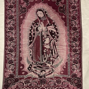 May include: Burgundy tapestry depicting the Virgin Mary with a halo, stars, and floral border. The tapestry has a fringed bottom and is made of woven fabric. The image shows the Virgin Mary with hands clasped in prayer.