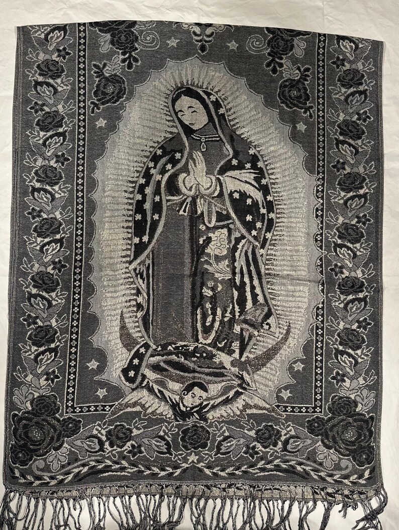 May include: A grey and black woven shawl depicting the Virgin Mary. The central image is framed by a floral border with roses and stars. The bottom edge has a fringe.