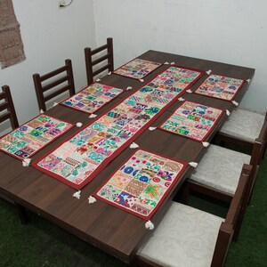 Puede incluir: Una mesa de comedor de madera marr&oacute;n oscuro con seis sillas a juego con cojines de colores claros. La mesa est&aacute; decorada con un camino de mesa rectangular de patchwork y seis manteles individuales rectangulares a juego, todos con borlas blancas.