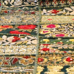 Puede incluir: Un tejido de color verde oscuro que presenta una cuadr&iacute;cula de parches rectangulares. Cada secci&oacute;n est&aacute; decorada con intrincados bordados en hilo dorado, rojo, blanco y naranja, con motivos florales, patrones geom&eacute;tricos y cuentas met&aacute;licas.