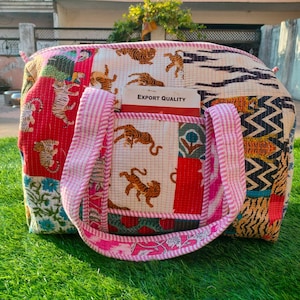 Könnte beinhalten: Patchwork-Tragetasche mit verschiedenen Mustern, darunter Tiger, Blumenmuster und geometrische Formen. Sie hat einen rosa gestreiften Griff und eine Tasche mit dem Text "EXPORT QUALITY".
