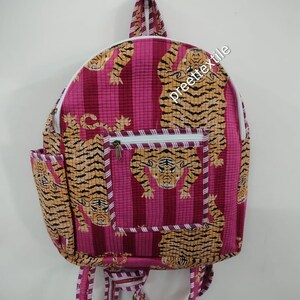 May include: A pink and magenta striped backpack featuring a tiger print. The backpack has a front zipped pocket, side pocket, and adjustable straps. The text "preette textile" is printed on the side.