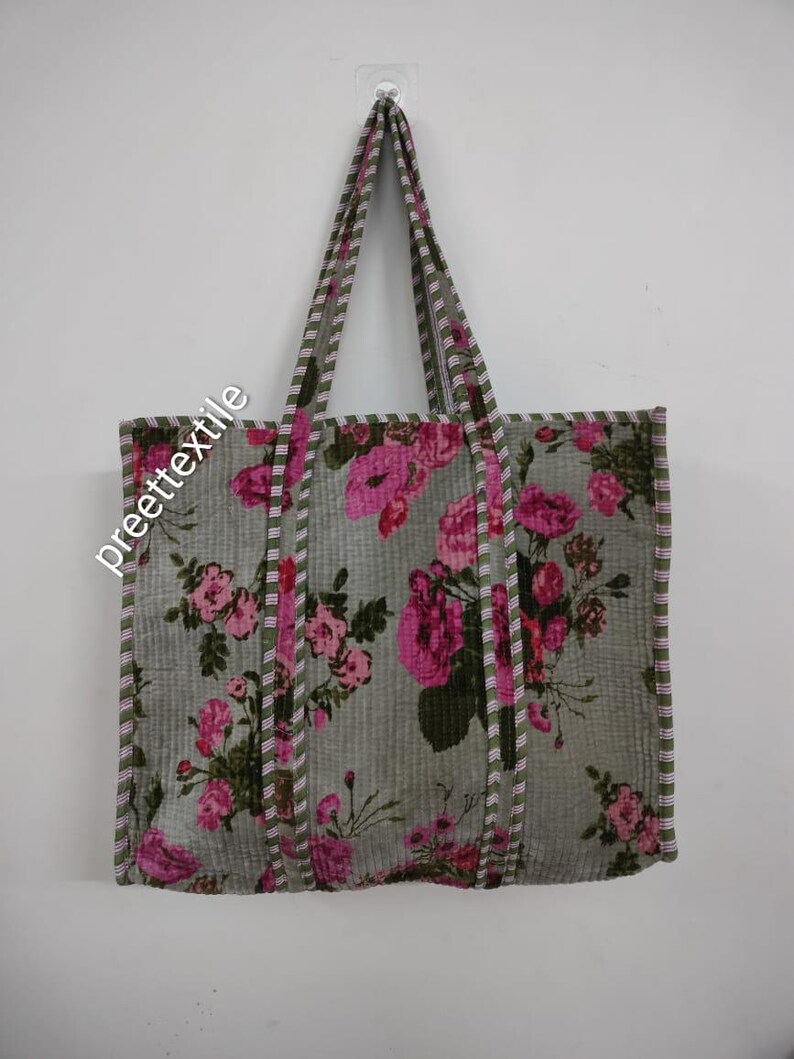 Puede incluir: Un bolso tote gris con un estampado floral de rosas rosas. El bolso tiene asas y ribetes a juego con un dise&ntilde;o a rayas. El texto "preette textile" est&aacute; impreso en el bolso.