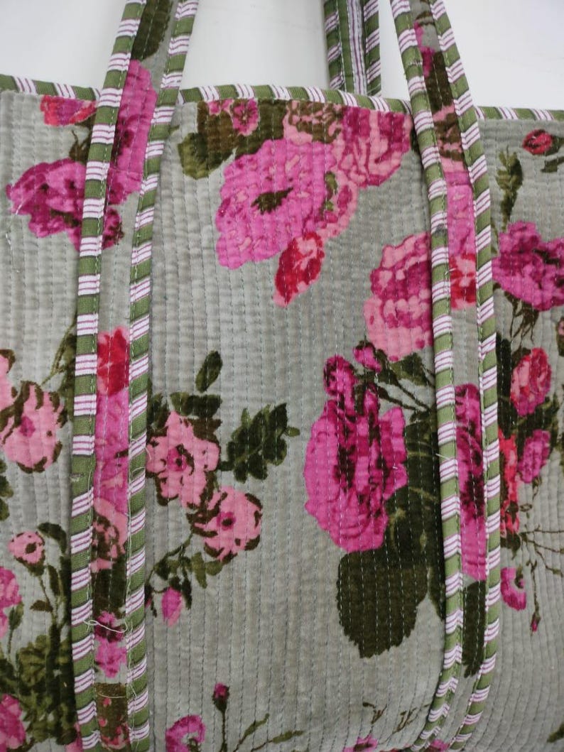 Puede incluir: Bolso tote acolchado con estampado floral. El bolso presenta grandes rosas rosas sobre un fondo verde claro. Las asas y los bordes est&aacute;n ribeteados con tela a rayas verdes y rosas. El bolso tiene un dise&ntilde;o acolchado vertical.