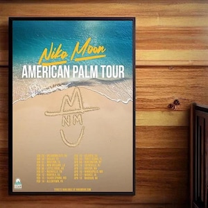 May include: A framed poster for the Niko Moon American Palm Tour. The poster features a beach scene with the tour name in yellow and a sand drawing of a hat and initials. Tour dates are listed below.