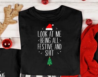 May include: Black Christmas family matching pajama sets. Each shirt has a Santa hat and Christmas tree graphic with the text "LOOK AT ME BEING ALL FESTIVE AND SHIT". The pajamas include a short-sleeve shirt, long-sleeve shirt, and a baby onesie.