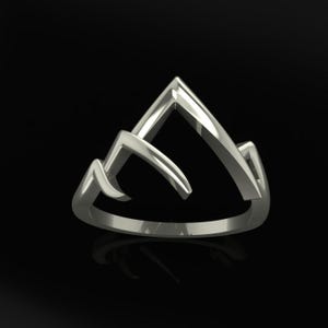 May include: A silver-colored ring with a mountain range design. The ring features three peaks of varying heights, with a smooth, polished finish. The ring is set against a black background, highlighting its reflective surface.