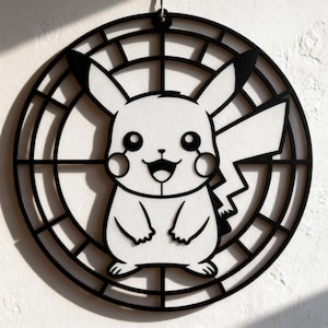 May include: Black and white Pikachu wall art. The design features a smiling Pikachu character inside a circular frame with a grid pattern. The artwork is suspended by a small metal loop at the top, suitable for hanging.