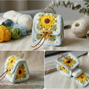 May include: A small, square, crocheted pouch featuring a sunflower motif in yellow, brown, and green on a cream background with light blue trim. It includes a gold-tone metal ring at the top, a wooden toggle closure with a brown cord, and a white case inside.