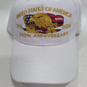 May include: White baseball cap with embroidered text and design. The cap features the words "United States of America" and "250th Anniversary" with the years 1776 and 2026. The design includes an eagle, the American flag, and a bell.