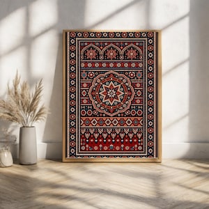 May include: A framed print featuring a detailed, symmetrical design reminiscent of a traditional rug. The artwork showcases a central starburst pattern in shades of red, orange, and blue against a black background, framed in a gold tone.