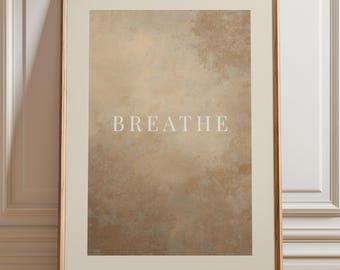 May include: Framed art print with the word "BREATHE" in white capital letters. The artwork features a textured, abstract design in shades of beige and brown. The print is set within a cream-colored mat and a gold-toned frame.