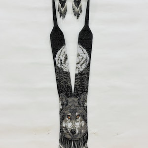Flat lay of handcrafted wolf seed bead necklace with matching fringe earrings displayed together on a white background.
